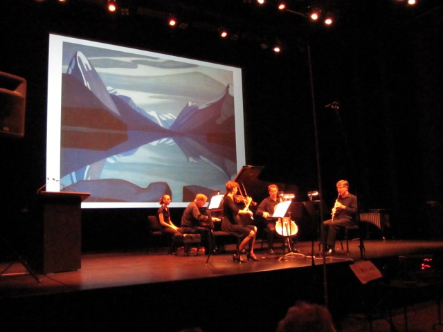 The painting "Maligne Lake" by Lauren Harris is the backdrop of a performance of Mack's composition of the same name, part of his piece "A Canadian Gallery"