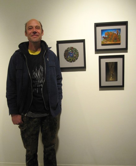 Eric Stotik posing beside three of his paintings at the Laura Russo Gallery in Portland, Oregon on Saturday, December 7, 2013 (photo by Anita Malhotra)